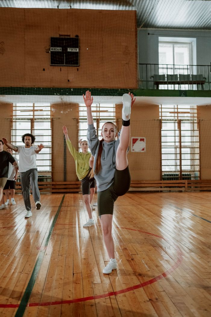 Group of young adults practicing dance routines, showcasing flexibility and teamwork indoors.